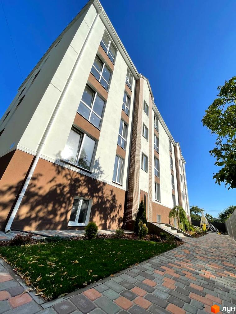 Будинок житлового комплексу SMART IDEA з коричневим та білим фасадом, вікнами та бруківкою на прибудинковій території.