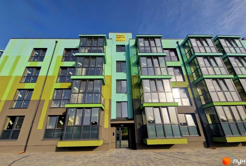 Зовнішній вигляд житлового комплексу Квітковий з яскравим фасадом та великими вікнами. На фасаді розміщено оголошення про продаж квартир.