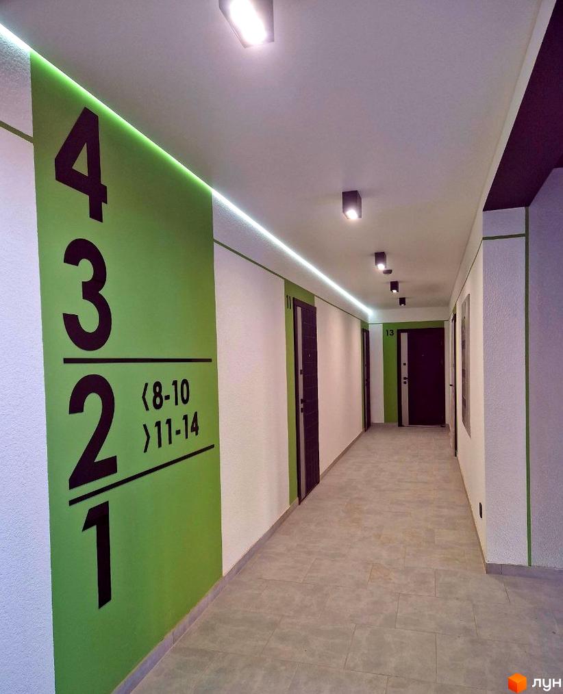 Коридор новобудови ЖК Квітковий з номерами квартир на стіні. Зовнішній вигляд будинку та прибудинкової території.