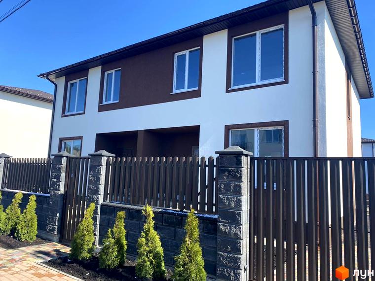 Котеджне містечко Житомирський дворик - 2. Фасад будинку білого та коричневого кольору з великими вікнами, огороджений дерев'яним парканом та кам'яними стовпами.