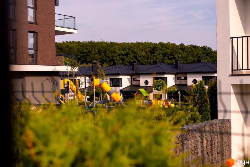 Зовнішній вигляд будинків житлового комплексу КМ SHERWOOD з дитячим майданчиком та зеленою зоною. Новобудова з сучасним дизайном та комфортною прибудинковою територією.