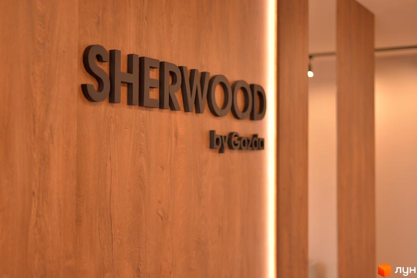 Житловий комплекс SHERWOOD від Gazda. Фасад будинку з дерев'яним оздобленням та підсвіткою.