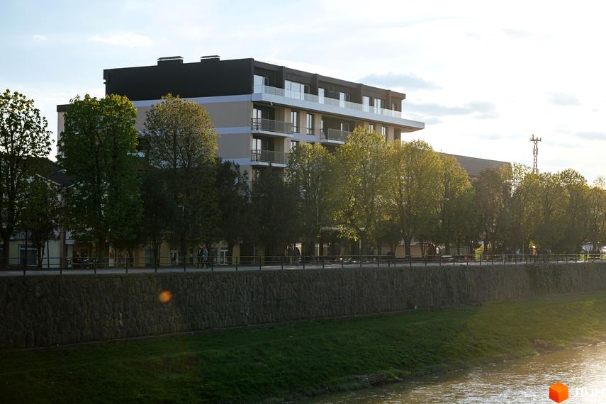 Новобудова ЖК RIVER LAND з балконами та скляними огорожами на тлі дерев та річки. Сучасний житловий комплекс з багатоповерховими будинками та зеленою прибудинковою територією.