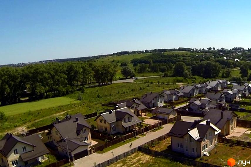 Котеджне містечко Наше містечко. Візуалізація котеджів з темними дахами та світлими фасадами, розташованих серед зеленої території з деревами та газонами.