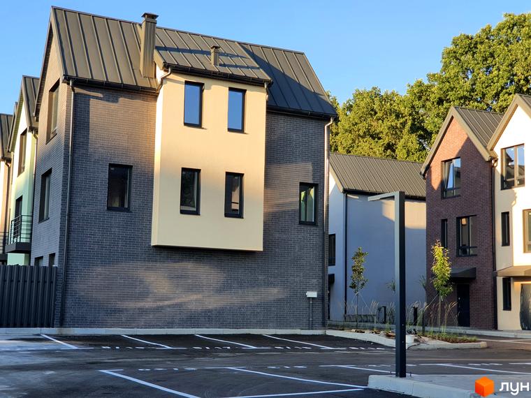 Зовнішній вигляд таунхаусів New Smart 11 з цегляним фасадом та сірим дахом, прибудинкова територія з парковкою та освітленням.