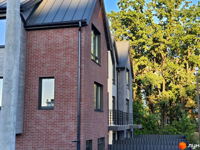 Таунхауси New Smart 11 з цегляним фасадом та великими вікнами на тлі зелених дерев. Зовнішній вигляд будинку та прибудинкова територія.