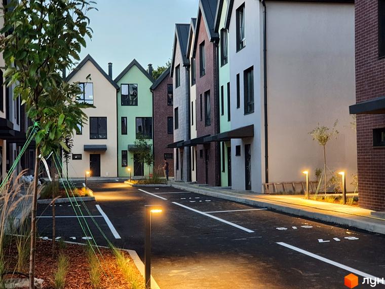 Таунхауси New Smart 11 з різнокольоровими фасадами та доглянутою прибудинковою територією з освітленням.