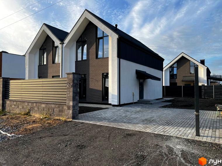 Котеджне містечко КМ New Village: фасади будинків з цегли та білої штукатурки, дахи темного кольору, вимощені дворики та паркани.