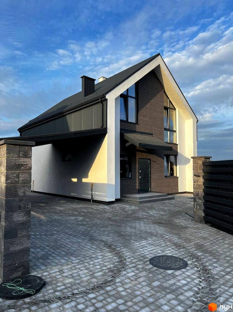 Котеджне містечко КМ New Village: двоповерховий будинок з темної цегли та білої штукатурки, навіс для авто та вимощена сіра плитка.