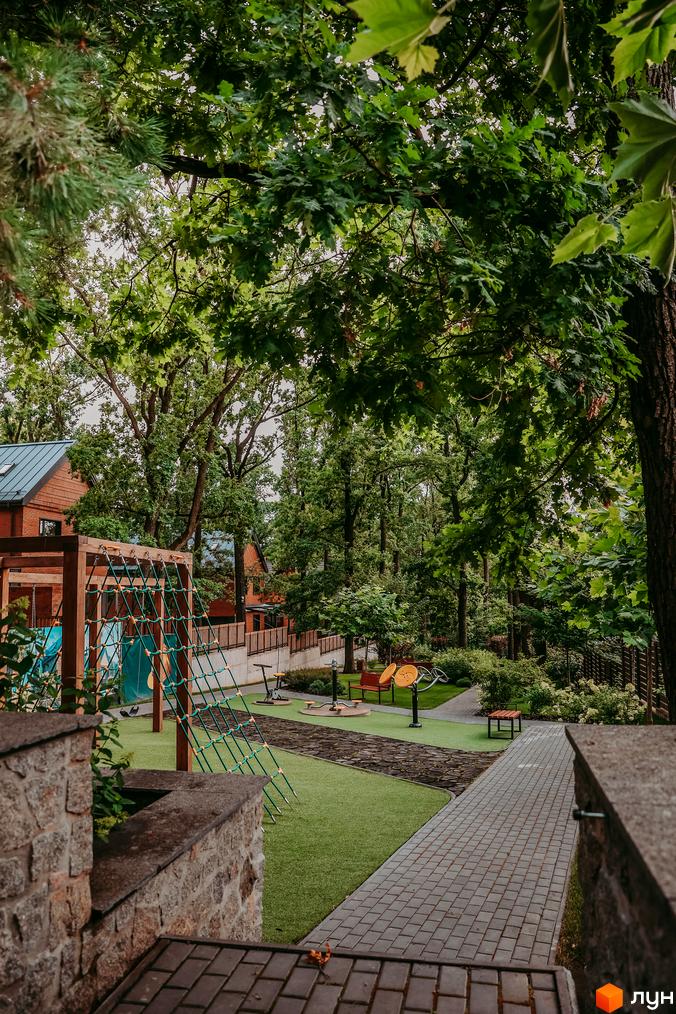 Котеджне містечко Oak Grove Town з цегляними будинками та дитячим майданчиком серед зелені. Доглянута прибудинкова територія з доріжками та ландшафтним дизайном.