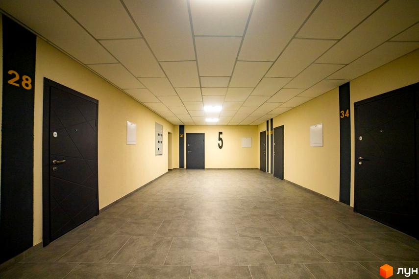 Внутрішній коридор Житлового комплексу Сонячний з темними дверима та номерами квартир 28, 31, 5, 34.