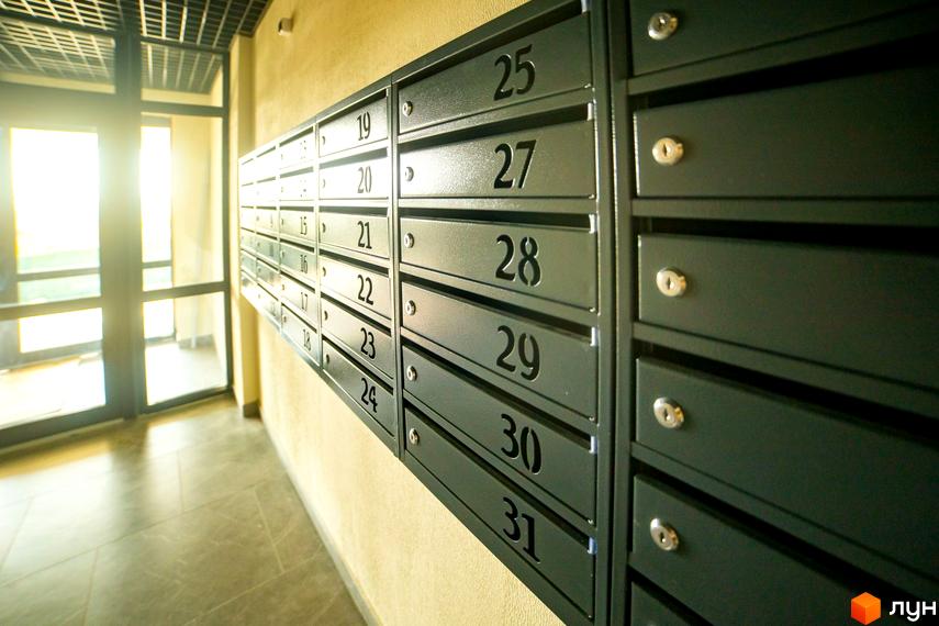 Секція поштових скриньок з номерами від 19 до 31 в новобудові ЖК Сонячний. Коридор з дверима та вікнами.