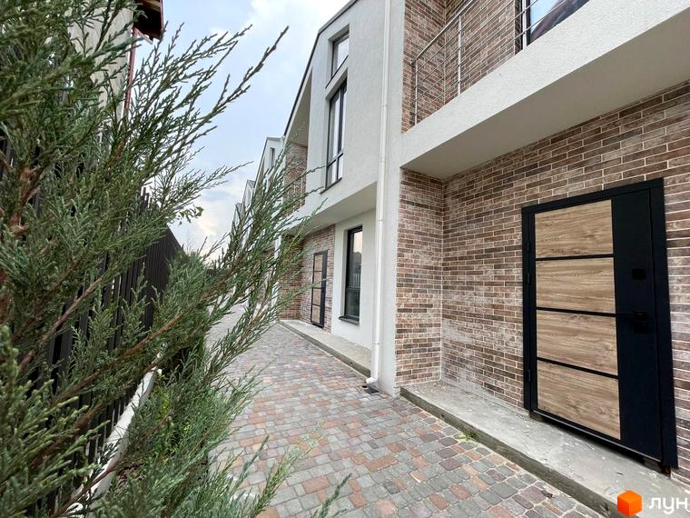 Таунхауси West Homes мають цегляний фасад та розташовані біля вимощеної доріжки.