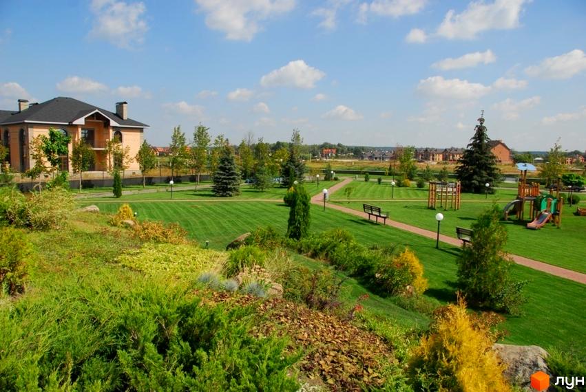 Котеджне містечко Вишневе містечко. На території комплексу розташований дитячий майданчик, зелені газони та доглянуті алеї. На фоні видно двоповерхові будинки.