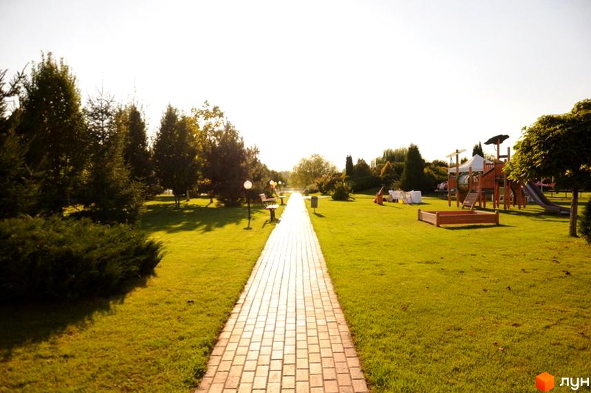Котеджне містечко КМ Вишневе містечко. Зелена доглянута територія з дитячим майданчиком та пішохідною доріжкою.