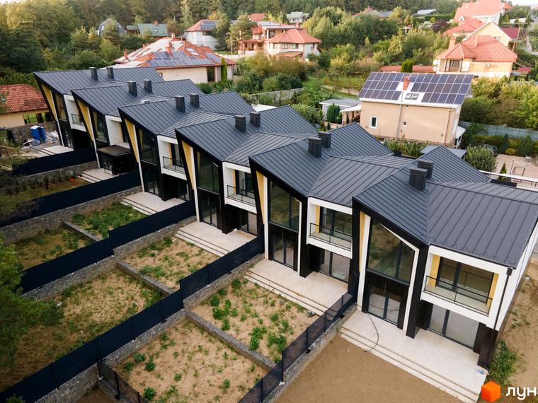 Сучасний житловий комплекс Таунхаус „ДЖЕРЕЛЬНА“ з унікальною архітектурою та прибудинковою територією. Зовнішній вигляд будинків вражає похилими дахами та великими вікнами.