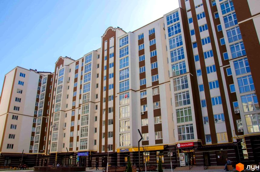Зовнішній вигляд житлового комплексу Millennium City з багатоповерховими будинками та великою кількістю вікон. На першому поверсі розташовані комерційні приміщення.