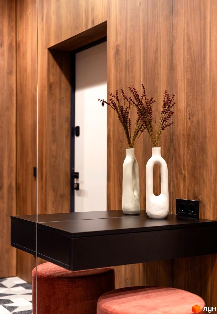 Інтер'єр ЖК Nebo з дерев'яними панелями та двома білими вазами з сухоцвітами на чорному консольному столику.