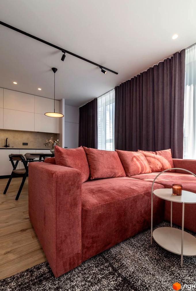 Інтер'єр вітальні з червоним диваном та столиком у ЖК Nebo. Сучасний дизайн квартири з кухнею та обідньою зоною.