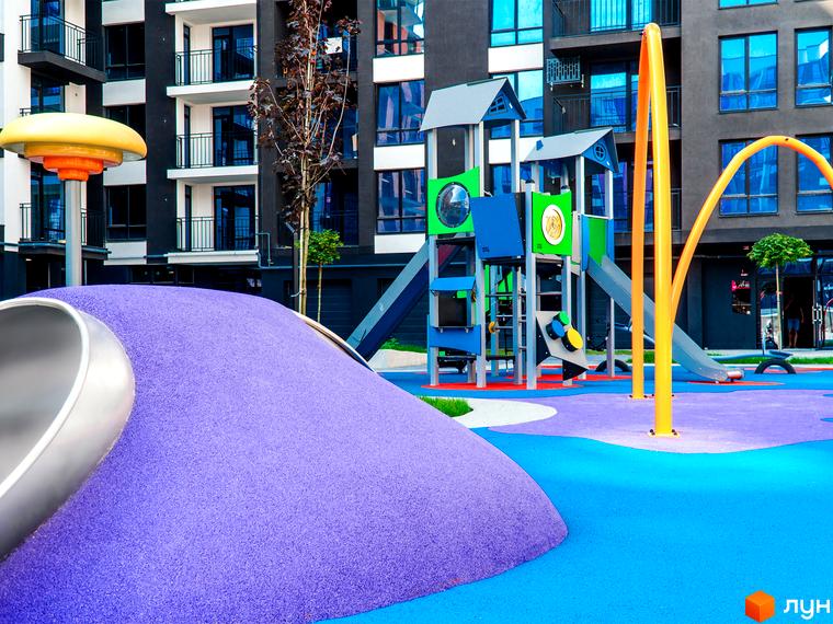 Фото ігрового майданчика біля багатоповерхового будинку в Житловому комплексі Family Plaza. На території є гірки та інші розваги для дітей.