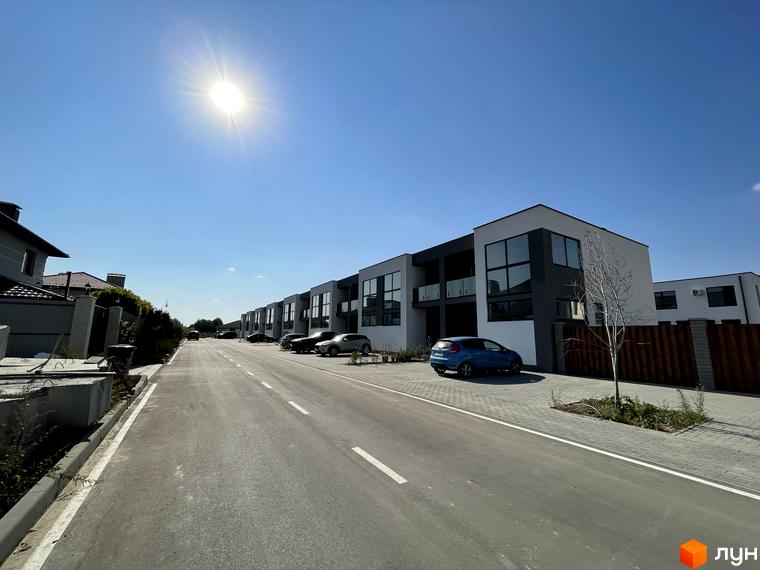 Котеджне містечко Osocor House. Зовнішній вигляд будинків з великими вікнами та прибудинкова територія з дорогою та паркуванням.