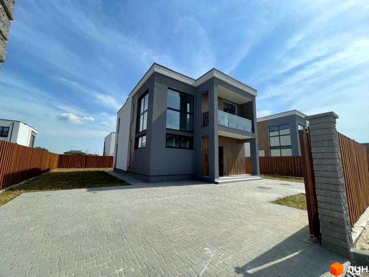 Котеджне містечко Osocor House: сірий двоповерховий будинок з великими вікнами та скляним балконом, вимощена сіра доріжка та дерев'яний паркан.