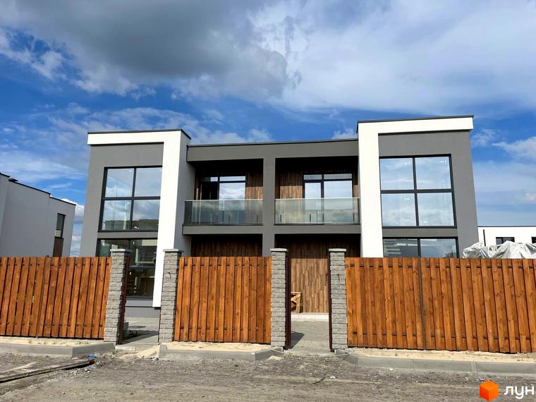 Котеджне містечко Osocor House. Фасад будинку з великими вікнами та дерев'яним парканом перед ним.