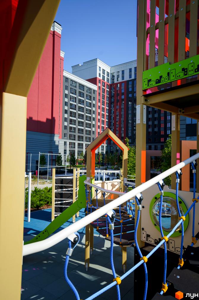 Житловий комплекс Irpin City з яскравим дитячим майданчиком. Сучасні багатоповерхові будинки з червоними та сірими фасадами.