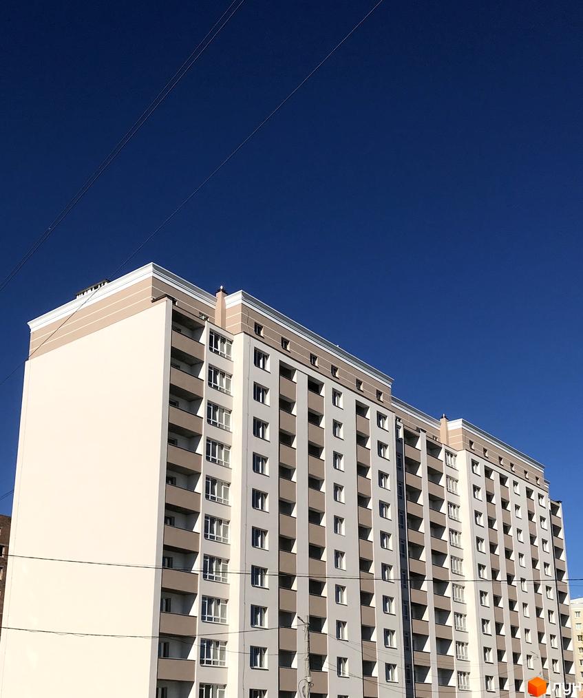 Зображення фасаду багатоповерхового будинку в Житловому комплексі Новобудова. На фото видно вікна та балкони, а також частину прибудинкової території.