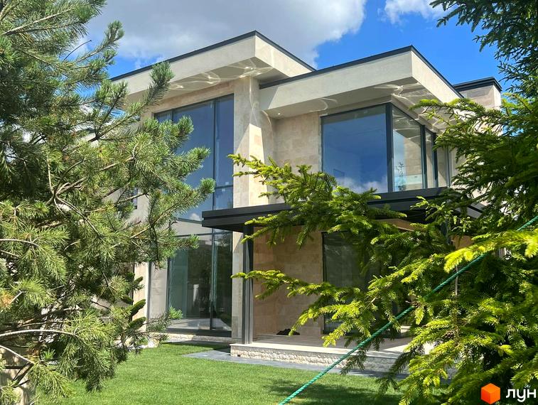 Зовнішній вигляд будинку в Котеджному містечку Riviera City Park з великими вікнами та доглянутим газоном. Навколо будинку зелені насадження.