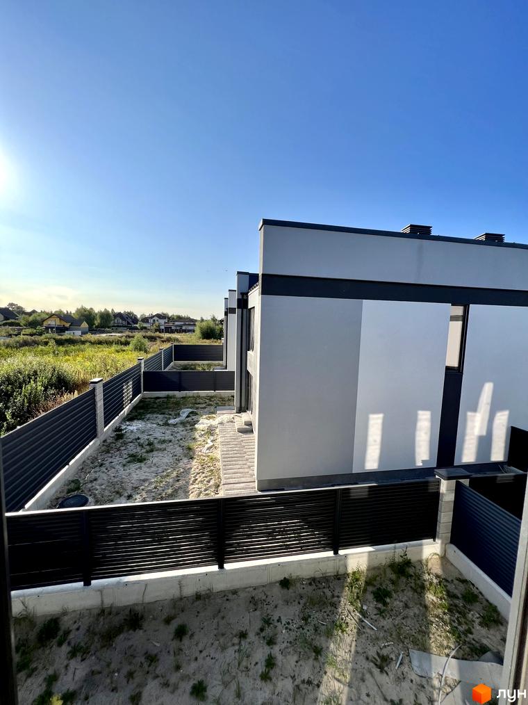 Котеджне містечко GREAT OSOCOR Apartments: сучасні будинки з сірими фасадами та чорними парканами, огороджують приватні ділянки з піщаним покриттям.