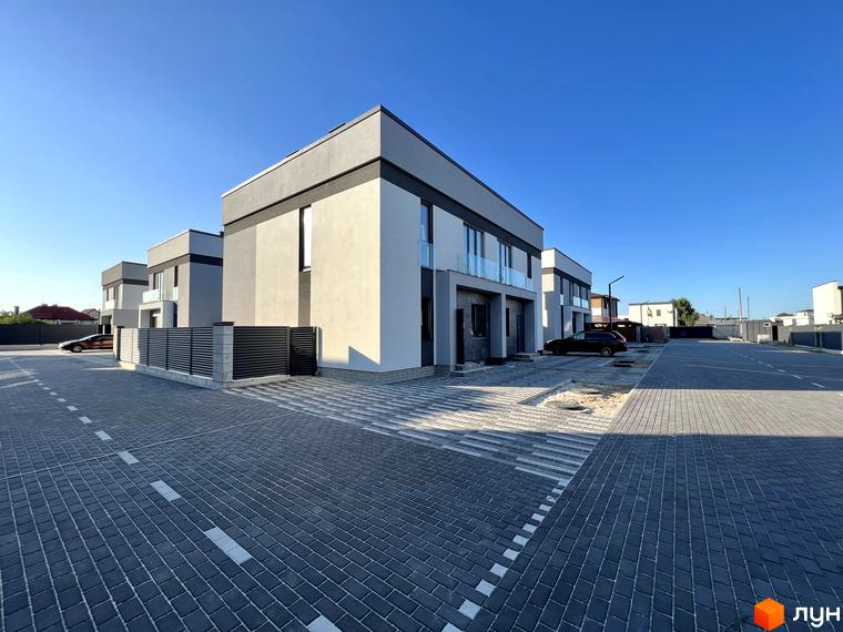 Зображення Котеджного містечка GREAT OSOCOR Apartments. Двоповерхові будинки з сірими дахами та парковкою, викладеною бруківкою.