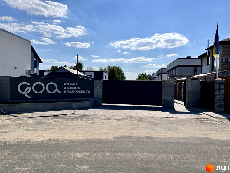 Котеджне містечко GREAT OSOCOR Apartments з сучасними будинками та огородженою територією під блакитним небом. На території розташована брама та паркан.
