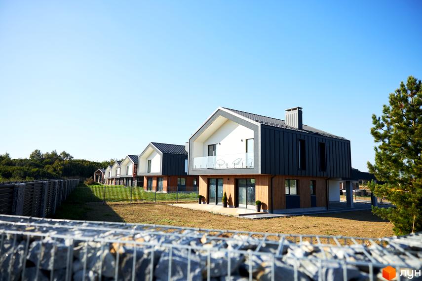 Котеджне містечко OZON Village. Будинки мають комбіновані фасади, балкони та великі вікна. Територія облаштована ділянками з травою та огорожею.