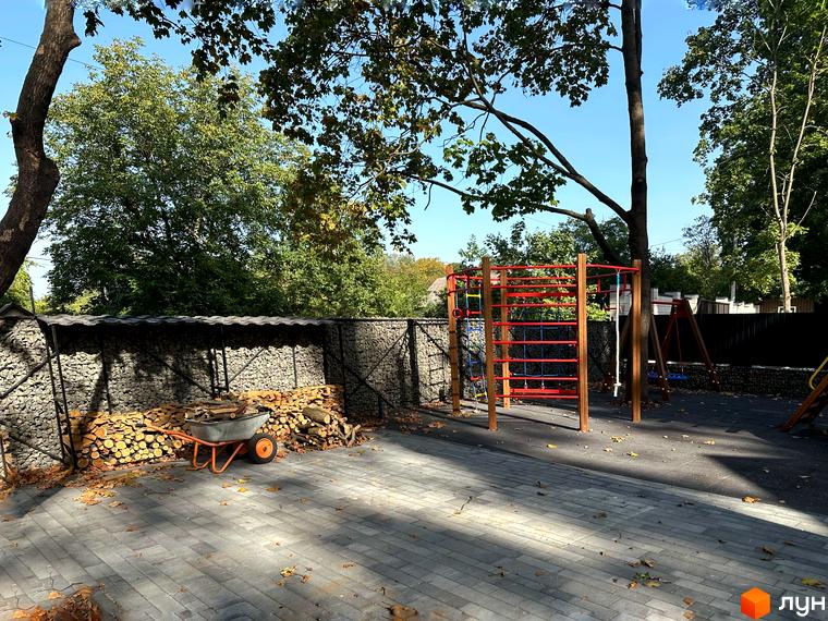 Зображення дитячого майданчика на території Котеджного містечка Lake View. На задньому плані видно паркан з каміння.