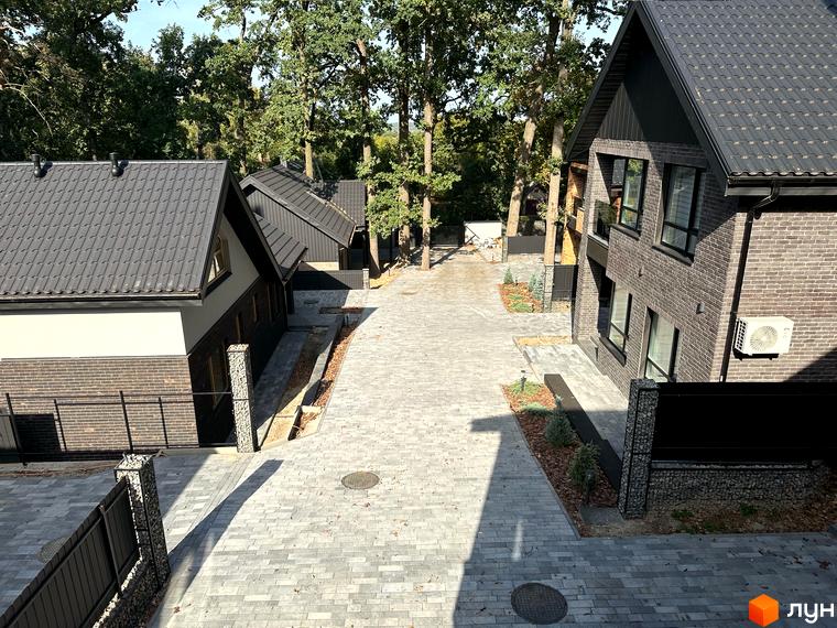 Котеджне містечко KМ Lake View. Зовнішній вигляд будинків з темним дахом та цегляними фасадами, вимощені доріжки та зелені насадження.