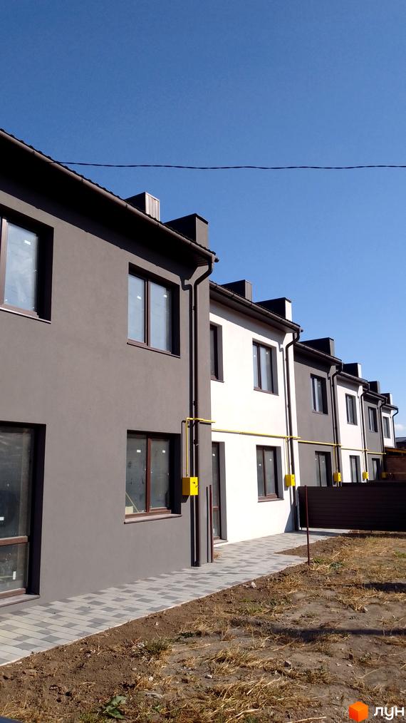 Зовнішній вигляд таунхаусів на Петриківській, 12. Двоповерхові будинки з сірим та білим фасадом, вимощені тротуари та невеликий двір.