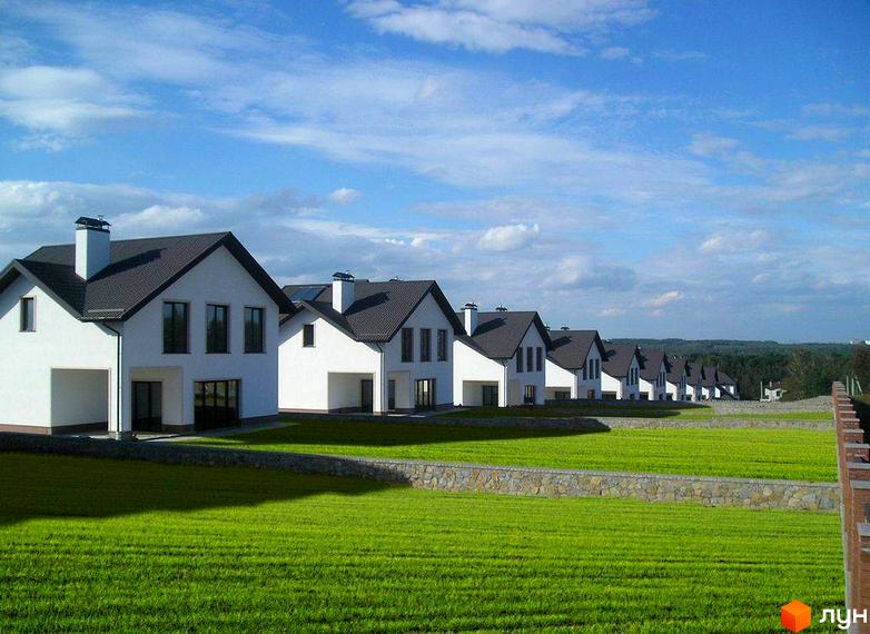 Фото Котеджне містечко Іванковичі з будинками в ряд. Білі будівлі з темними дахами та великим газоном перед ними.