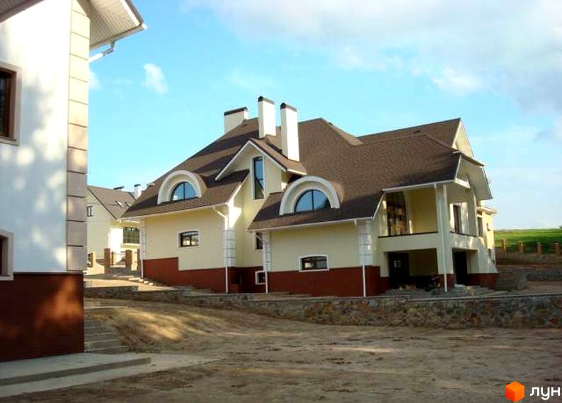 Зображення Котеджного містечка Іванковичі: двоповерховий будинок з коричневим дахом та світлим фасадом. Навколо будинку незавершений ландшафтний дизайн.