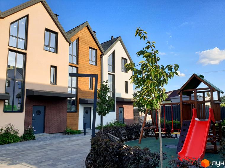 Таунхауси New Smart 6 з фасадами світло-бежевого та дерев'яного кольору. Поруч дитячий майданчик з гіркою та гойдалками.