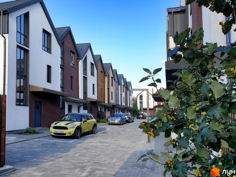 Таунхауси New Smart 6 з цегляним та білим фасадом, розташовані на вимощеній вулиці з припаркованими автомобілями.