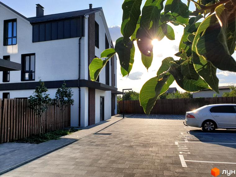 Таунхауси New Smart 6: двоповерхові будинки з білою штукатуркою та темними елементами фасаду, парковка з бруківки та дерев'яний паркан.