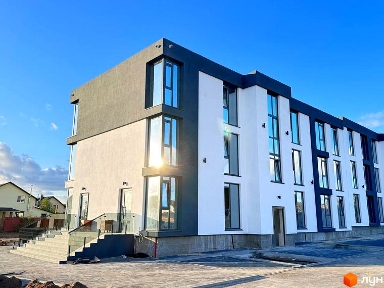 Будівельний проєкт Aura Park – сучасна новобудова з біло-сірими фасадами та великими вікнами на тлі блакитного неба. Поруч розташовані сходи з прозорими поручнями.