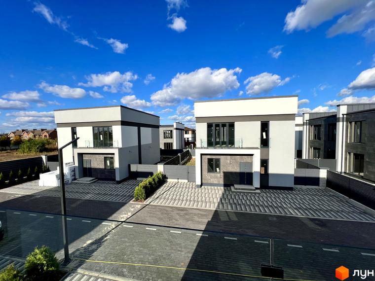 Котеджне містечко GREAT OSOCOR Apartments: двоповерхові будинки з сірими та білими фасадами, великими вікнами та скляними балконами. Прибудинкова територія вимощена плиткою, огороджена парканом, з доглянутими зеленими насадженнями.