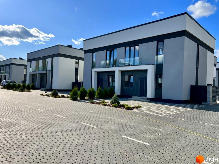 Зовнішній вигляд будівель котеджного містечка GREAT OSOCOR Apartments з сірими та білими фасадами, скляними балконами та бруківкою на прибудинковій території.