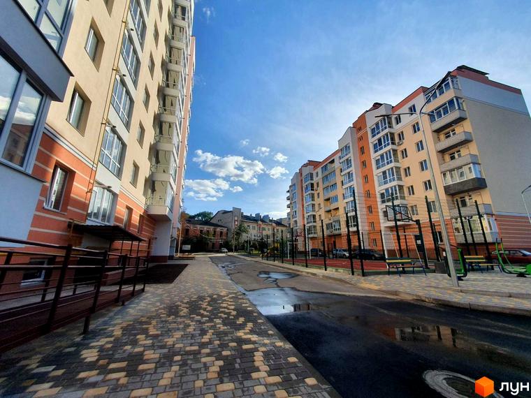 Новобудова Зоря з багатоповерховими будинками бежево-помаранчевих відтінків. На прибудинковій території облаштовано спортивний майданчик.