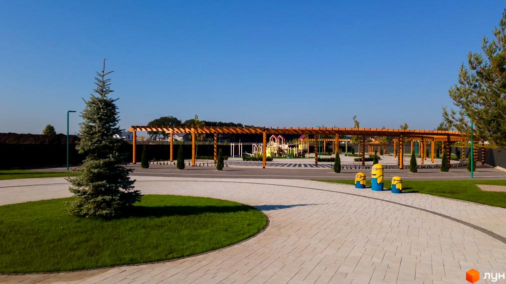 Оздоблені деревом арки над дитячим майданчиком у Містечку котеджів Beverly Hills Residence. Зелені насадження та доріжки для прогулянок.