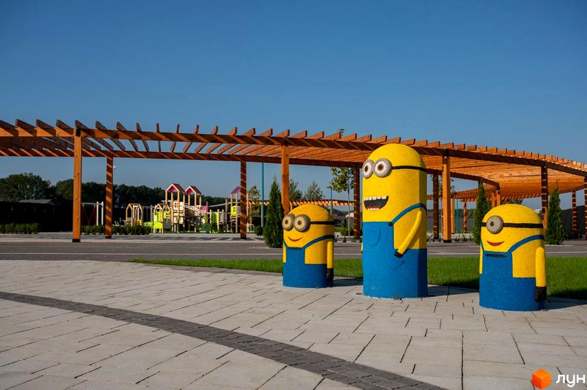 Котеджний комплекс КМ Beverly Hills Residence з дитячим майданчиком та фігурами міньйонів на фоні дерев'яної альтанки.
