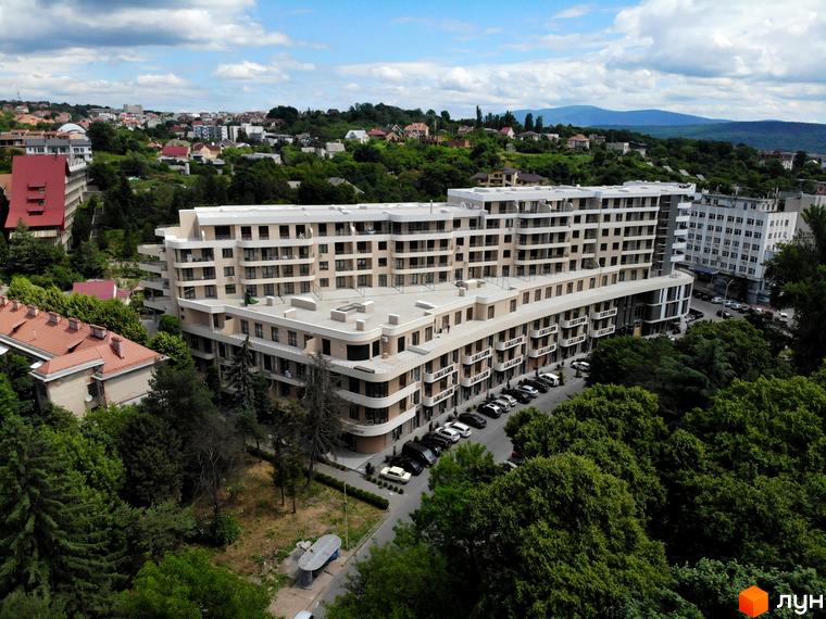 Зовнішній вигляд новобудови ЖК DREAM CITY з балконами та паркінгом. Навколо комплексу зелені насадження та міський пейзаж.