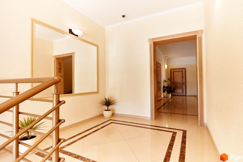 Вхідна група житлового комплексу САКУРА з дзеркалом та перилами. Коридор з дверима та рослинами.